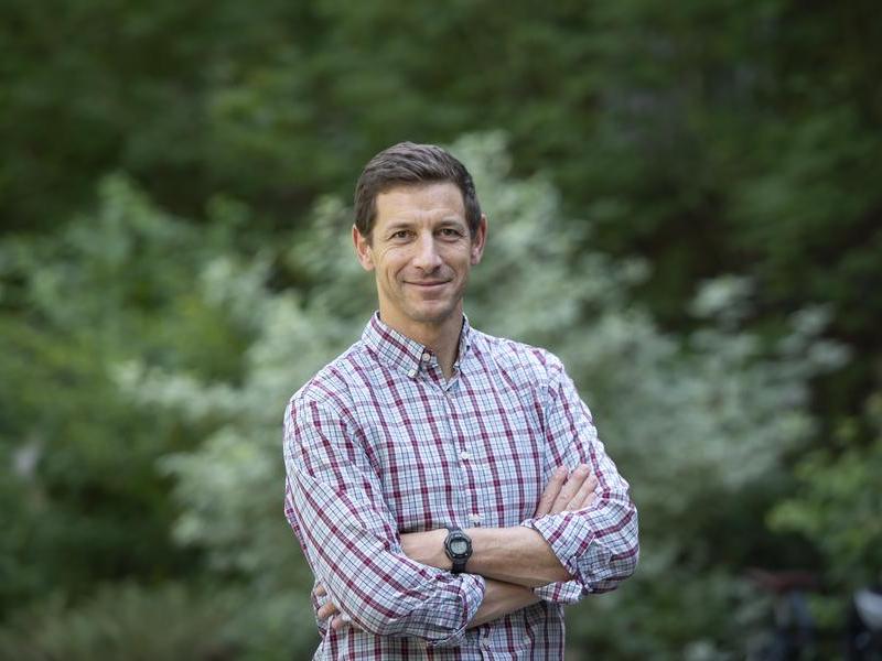 Photo portrait of Professor Josh Howe standing outside with trees in the background