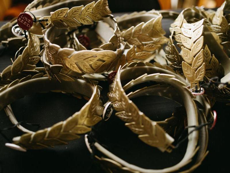 A pile of Reed laurels, gold in color, rest on a table. A pin that says Love Reed is attached to one.