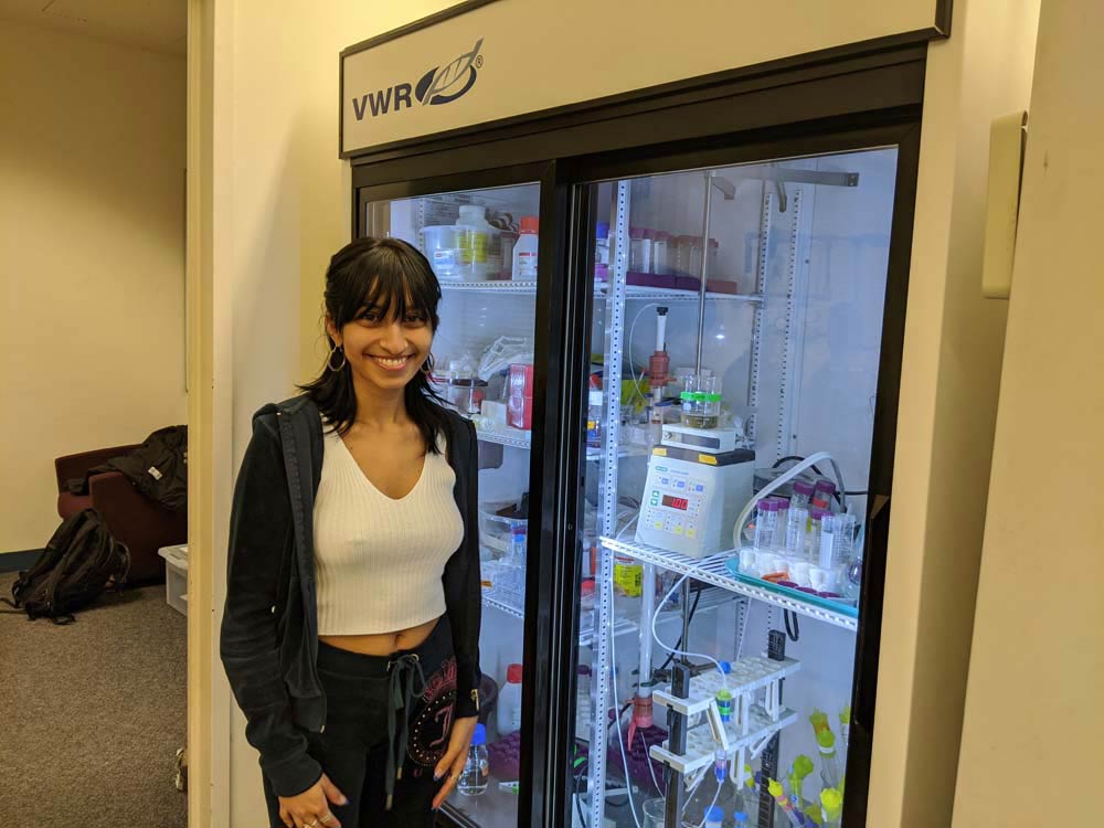 A student posing in front of a refrigerator full of samples