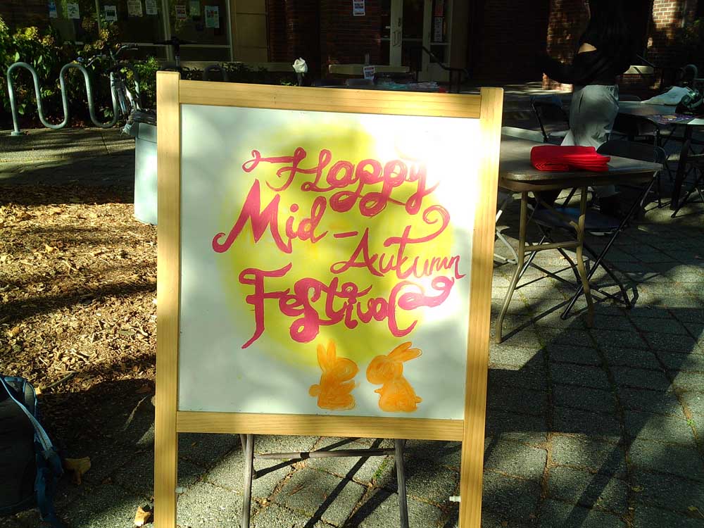 The sandwich-board sign reading "Happy Mid-Autumn Festival"