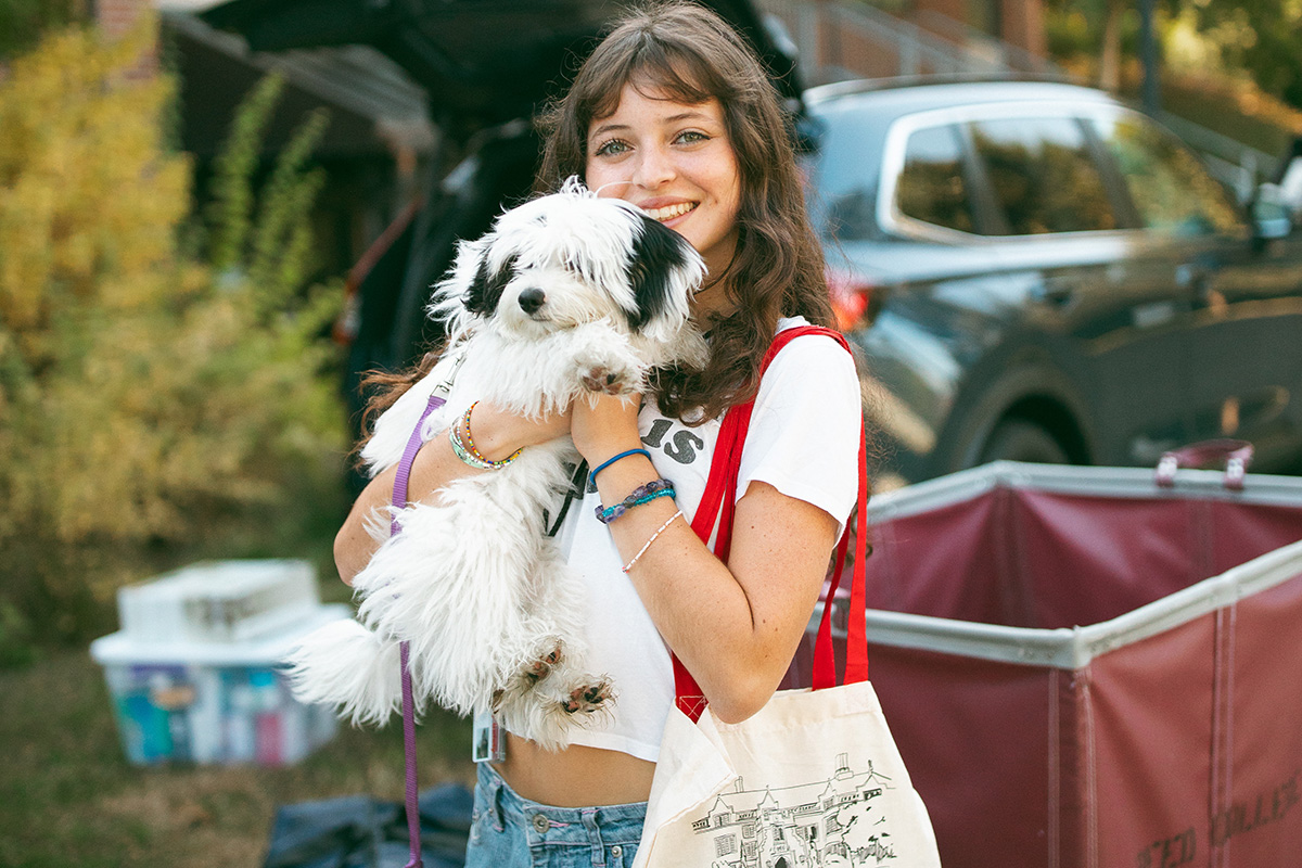 A student poses while clutching her dog 