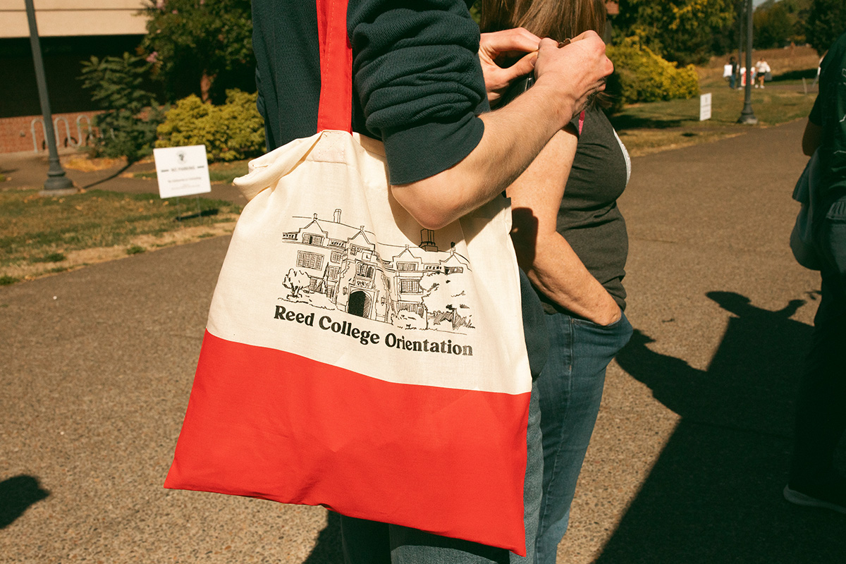 The Reed College Orientation tote, filled with Orientation materials and swag, worn by a student