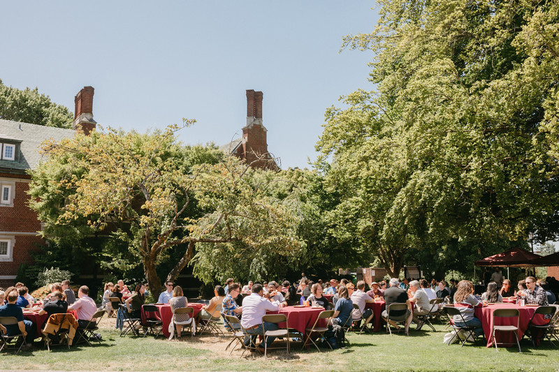 Reed College staff enjoying an outdoor picnic on tables in the sun