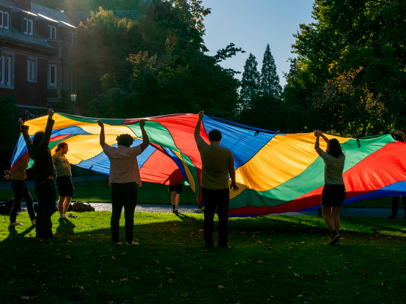 Students playing with a colorful parachute on a field