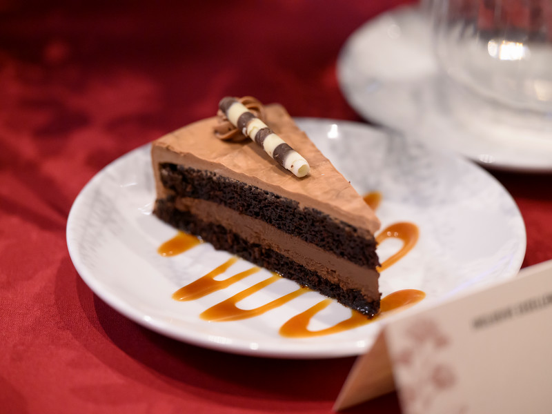 A slice of chocolate cake on a caramel drizzled ceramic dessert plate