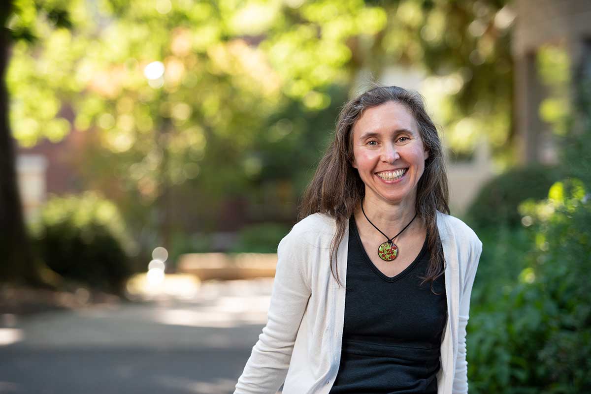 Exterior photo of woman in front of trees and greenery.