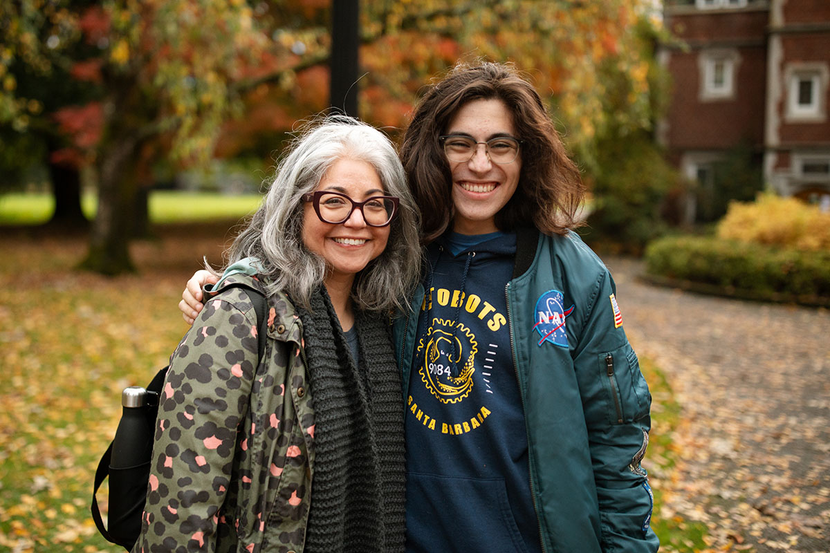 Student and their parent outdoors in front of colorful fall foliage