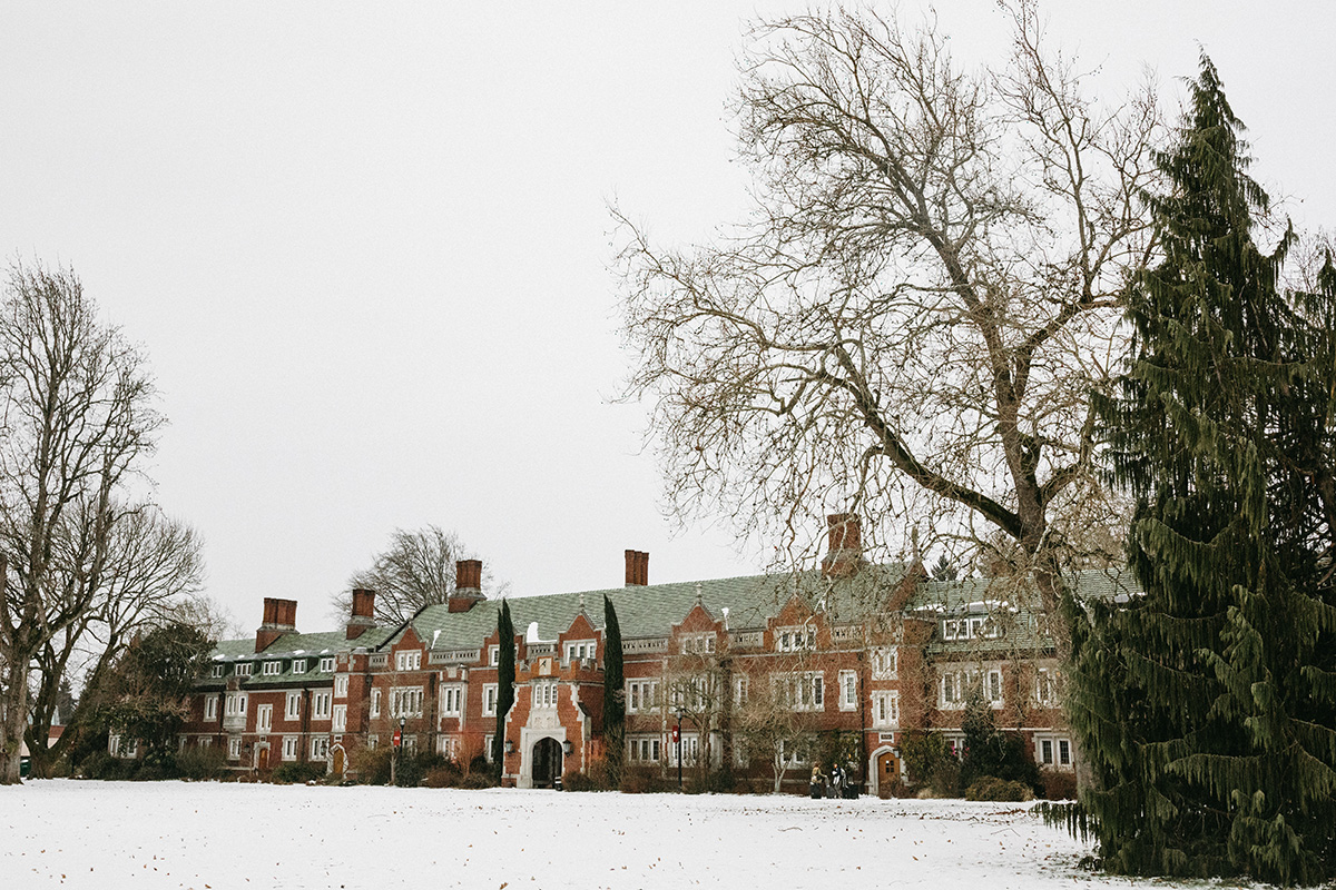 Broad campus photo of Old Dorm Block behind a snow-covered front lawn and bare trees.